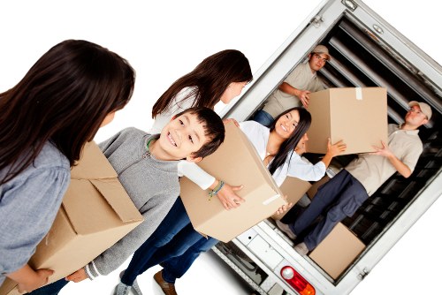 Removal van and moving team preparing household items for transport