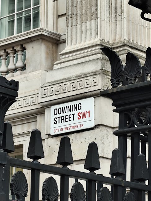 Close-up image of a white street sign attached to a stone building's facade on Downing Street in Westminster, London, indicating postcode SW1 and the City of Westminster. The sign is situated above a 