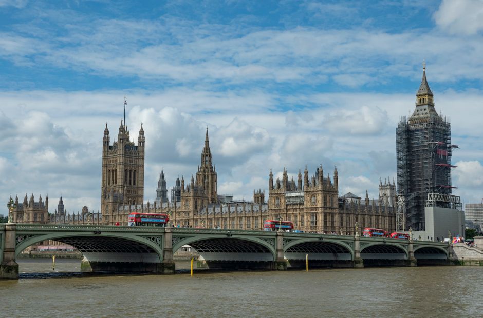 Close-up image of a white street sign attached to a stone building's facade on Downing Street in Westminster, London, indicating postcode SW1 and the City of Westminster. The sign is situated above a 